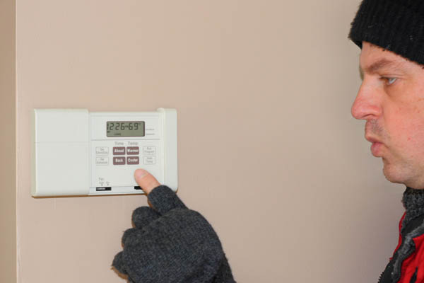 image of a homeowner adjusting a programmable thermostat for for furnace that isnt producing heat